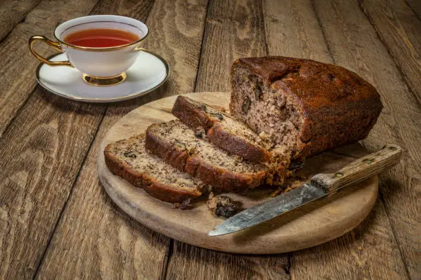 slices of fresh banana bread with walnut on a cutting board with a cup of tea