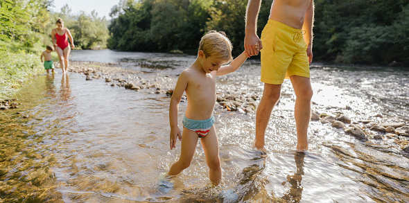 Photo of a young family with two children spending hot summer day on the river // wide photo dimensions