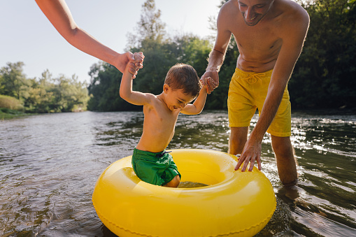 Photo of a young family with one boy spending hot summer day on the river