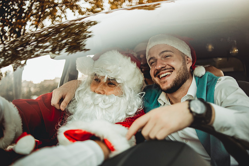 A merry party in the car with Santa Claus - The guy disguised as Santa Claus travels by car with his friends - The New Year's party can begin