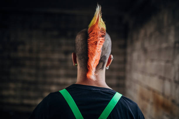 Rear view of young panker colorful coiffure Young male punker standing in abandoned warehouse. mohawk stock pictures, royalty-free photos & images