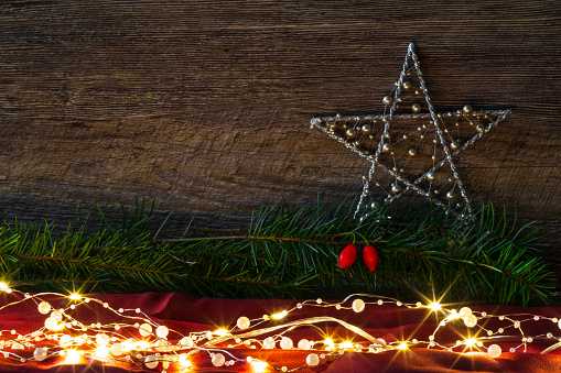 Festive Christmas star with glowing lights and pine branches.