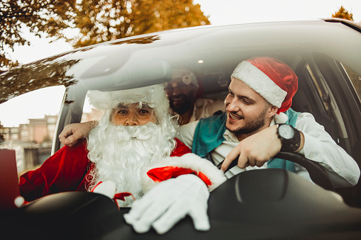 A merry party in the car with Santa Claus - The guy disguised as Santa Claus travels by car with his friends - The New Year's party can begin