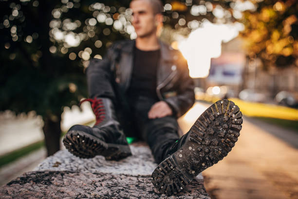 hombre punk persona en botas de combate sentado al aire libre en la ciudad - combat boots fotografías e imágenes de stock