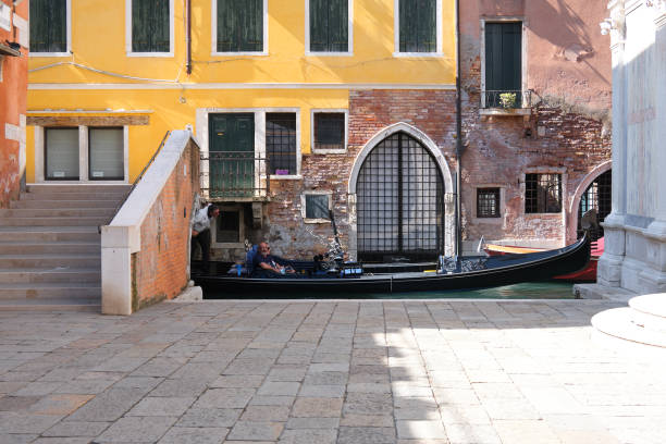 romantic old houses. gondola passes under pedestrian bridge across canal. hardly anybody outdoors. tourists are returning to venice, but far fewer than in recent years - travel outdoors tourist venice italy imagens e fotografias de stock