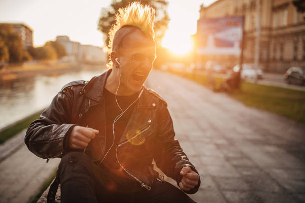 ヘッドフォンで音楽を聴いたり、路上で叫んだりするパンカー - mohawk river 写真 ストックフォトと画像