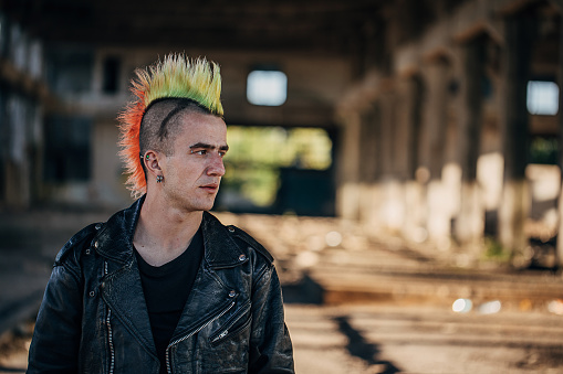 One young male punker standing in abandoned warehouse.