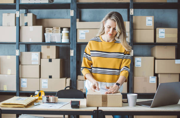 Mature woman running online store Mature woman at online shop. She is owner of small online shop. Receiving orders and packing boxes for delivery. packing stock pictures, royalty-free photos & images