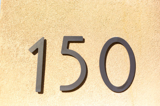 istock Sunlit Number 150 Street Address on Yellow Wall 1282211497