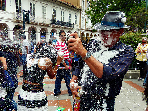 Cuenca, Ecuador - February 6, 2016: Man with a lot of foam on his faces and on clothes is spraying foam at people at traditional parade which holds during Carnival.