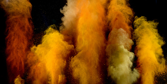 Color columns of smoke or powder against black background. Various tones of yellow powder. Frozen motion abstract background.