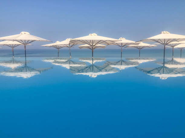 Beach umbrellas reflected in an infinit pool in Halkidiki Greece Beach umbrellas reflected in an infinit pool in Halkidiki Greece halkidiki beach stock pictures, royalty-free photos & images