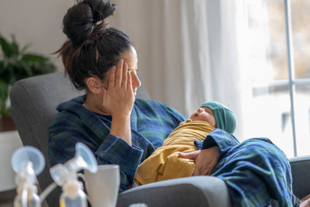 Tired new mother holding her baby Tired mother holding her newborn child at home after tying to pump. postpartum depression stock pictures, royalty-free photos & images