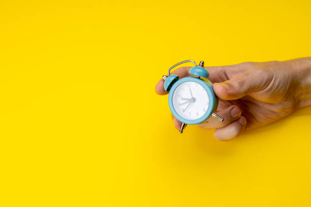 istock person holding old blue clock over yellow background. copy space. studio shot. time concept. schedule symbol 1282218857