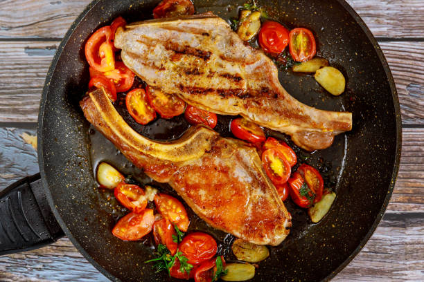 istock Fried steak with tomato and garlic in pan. 1282221448