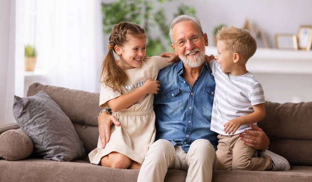 istock Grandfather hugging grandchildren on sofa 1282222375