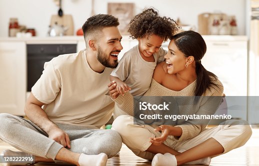 istock happy multiethnic family mom, dad and child  laughing, playing and tickles    on floor in cozy kitchen at home 1282222916