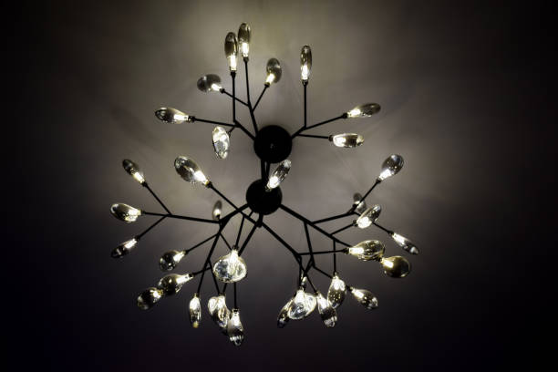 An electric chandelier with bright glowing bulbs hangs on the ceiling in the twilight. An electric chandelier with many bright glowing bulbs hangs on the ceiling in the twilight. chandelier earring stock pictures, royalty-free photos & images