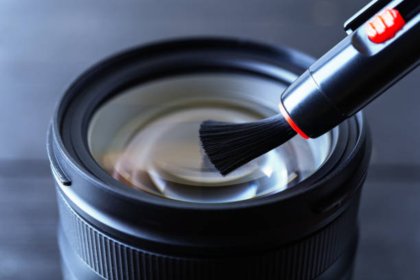 istock Sweeping dust from front lens using lens pen brush. Routine removal of dust and spots from photographic equipment. Maintenance close-up. 1282229877