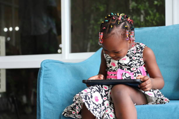 istock African American kid is homeschooling by learning from digital tablet while sitting on sofa at home 1282236082
