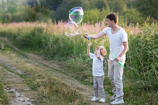 Happy family blow soap bubbles in nature in summer day