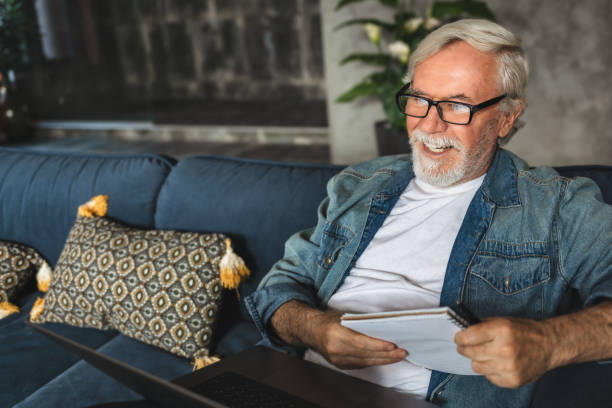 istock Smiling elderly professor conduct online lesson using laptop computer Senior man speak talk on video call while Sitting on sofa 1282252007