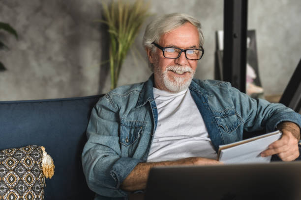 istock Senior man speak talk on video call while sitting on sofa elderly professor conduct online lesson using laptop computer 1282252542