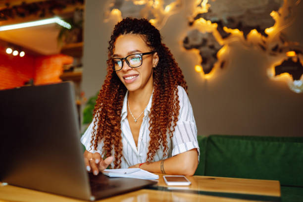 Young african american woman working online or studying on laptop computer at restaurant.