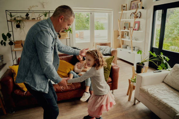 istock Cheerful father and daughter playing and dancing at home holding hands 1282258030