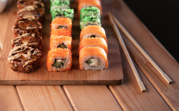 istock Sushi roll with chopsticks on a wooden stand on a wooden table. Sushi menu. 1282258149