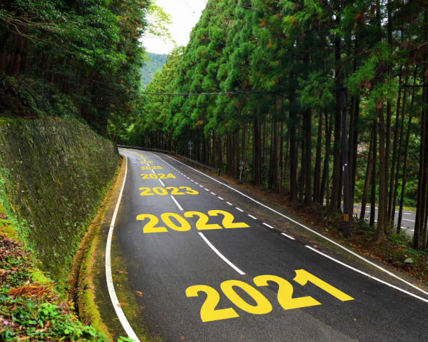 десять лет с 2021 по 2030 год на автомобильных дорогах и белых линиях разметки в лесу - future стоковые фото и изображения