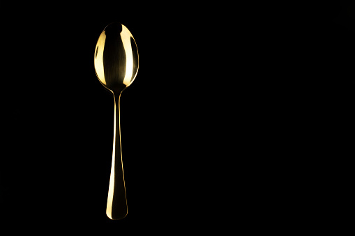 Gold spoon on a black background. Cutlery.