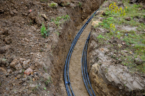 laying high voltage cables to the ground. the environment does not damage electric poles. Excavation meter deep in the ground black plastic coated strong cable wires. risk of electric shock in case of insulation failure. cover with sand and plastic protec optical, network, connection, underground, trench, datacenter, optics, soil, fiber, communication, telecommunications, site, internet, electrical, energy, ditch, industrial, pvc, pipeline, infrastructure, pipe, optic, outdoor, green, laying, high, voltage, cables, ground, environment, damage, electric, poles, pole, excavation, meter, digging, excavator, work, deep, black, plastic, coated, strong, cable, wire, wires, risk, injury, shock, insulation, failure, cover, sand, plastic protection, bundles, bundle, electricity, urban, two, lines, row, curved, bent steel cable stock pictures, royalty-free photos & images