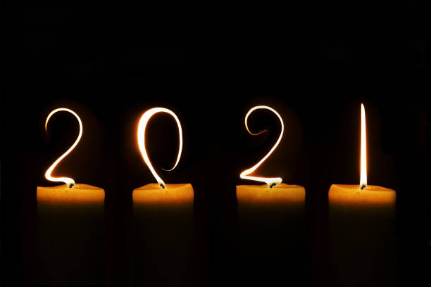 2021 written with candle flames on black background, greeting card