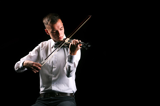 Young men playing the violin with black background