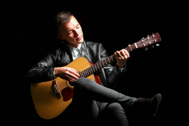 istock Young men playing the guitar with black background 1282263199