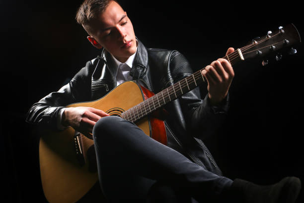 istock Young men playing the guitar with black background 1282263201