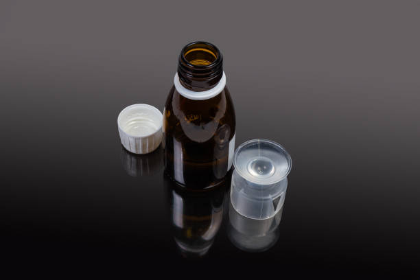 istock Liquid medicine in small bottle, measuring cup on dark surface 1282263388