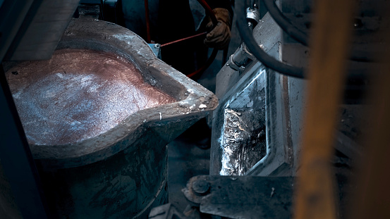 Ladle with molten metal is poured into a mold.