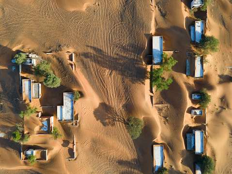 Aerial view of ghost village and abandoned houses in the UAE desert in Al Madam in Sharjah emirate near Dubai, overtaken by sand dunes which are covering and entering house remaining