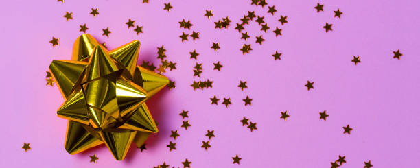 istock Gold bow with star glitter confetti on pink paper background. 1282265419