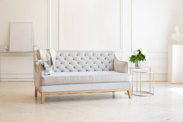 istock Modern Spacious minimalistic living room interior with a gray sofa and a coffee table with a vase with a bouquet of peonies flowers against a white wall. Scandinavian  interior home. Cozy room decor. 1282268541