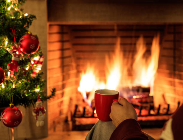istock Hand holding a mug of tea, logs burning in a fireplace 1282269161