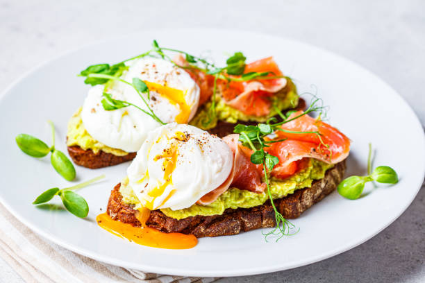 istock Toast with salmon, poached egg and avocado on white plate. Poached egg with salmon and guacamole on rye bread. 1282269939