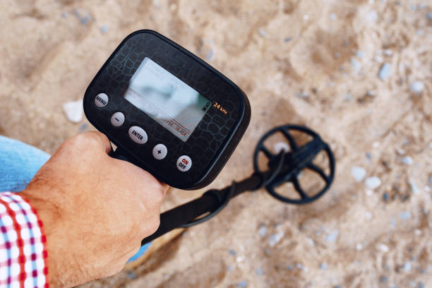 istock Male hand holding metal detector device above the ground 1282271271