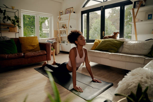 istock African woman lying on yoga mat at home doing stretching exercise 1282273273