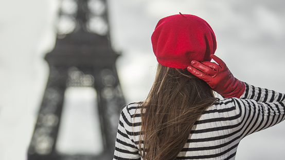Young stylish woman in red beret and autumn clothing oudoors with Eiffel tower