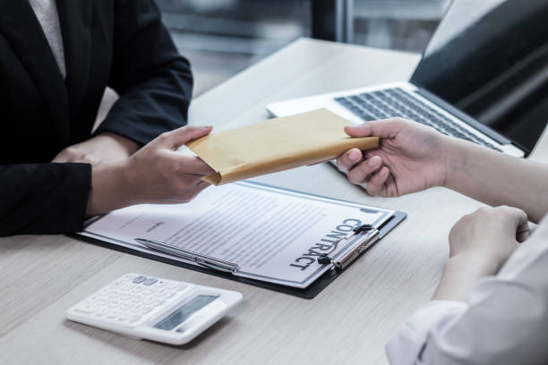 a mortgage broker handling an envelope to a woman