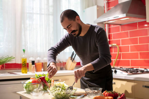 istock Man Mixing Salad with Lettuce and Parsley in Bowl 1282279345