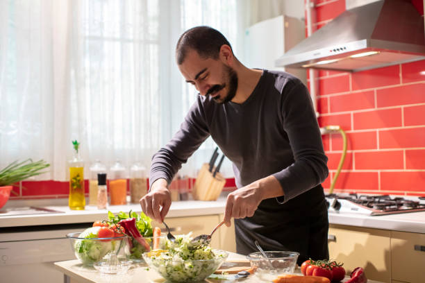 istock Man Mixing Salad with Lettuce and Parsley in Bowl 1282279739